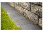 Graue Pflasterstein-Gartenbegrenzung mit grünem Gras und einer Steinmauer