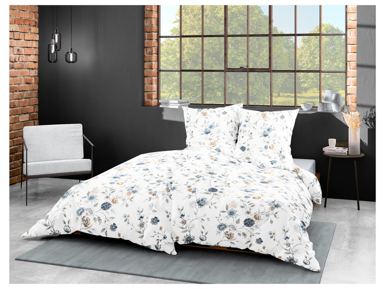 Ein weißer Bettbezug mit blauen Blumen und ein grauer Teppich.