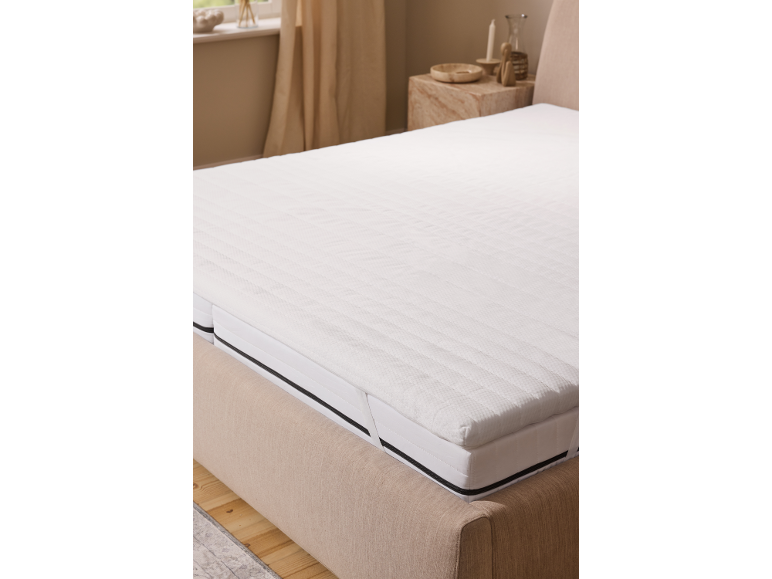Weißer Matratzentopper auf einem Bett in einem neutralen Schlafzimmer.