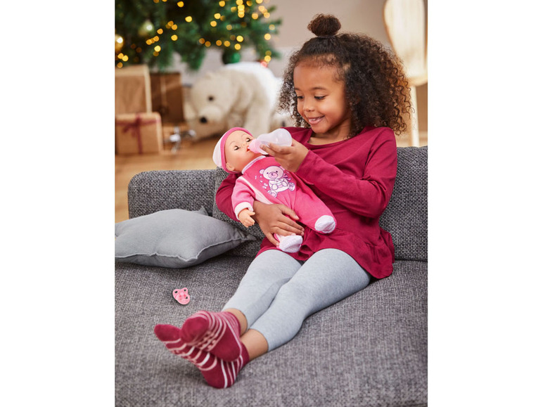 Ein Mädchen gibt einer Baby Born Puppe eine Flasche.