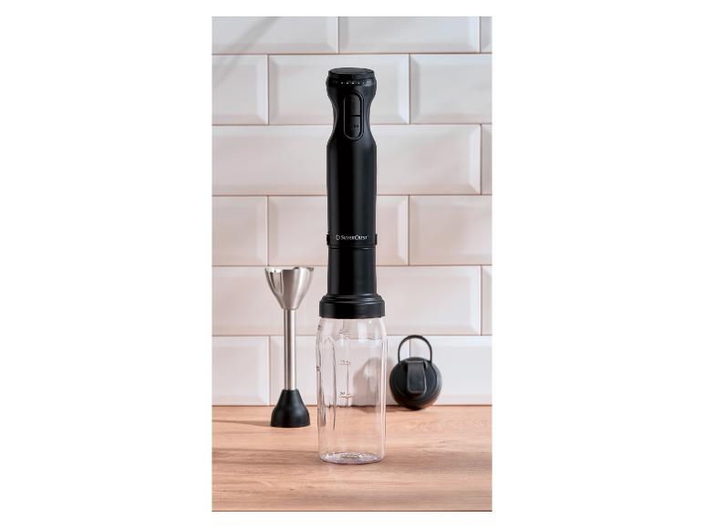 Schwarzer SilverCrest Stabmixer mit Messbecher und Schneebesen auf einer Holztheke.