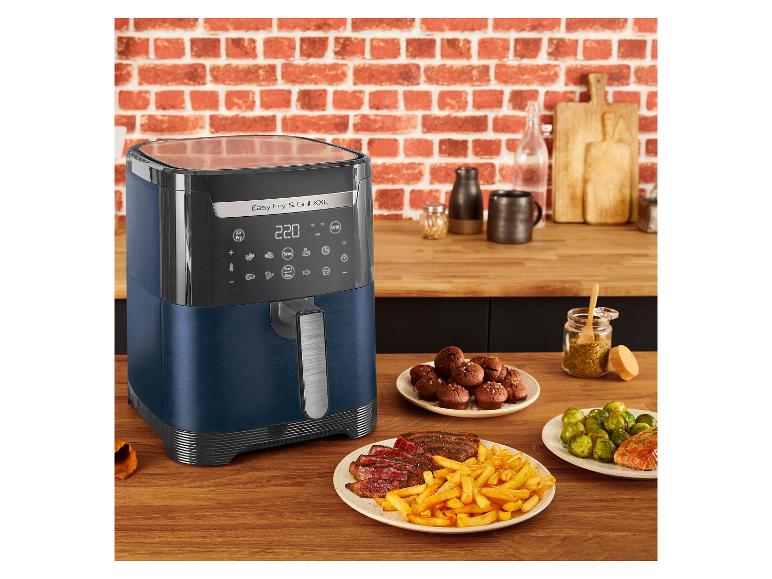 Eine blaue Heißluftfritteuse auf einer Küchenarbeitsplatte mit Essen und Zubehör.