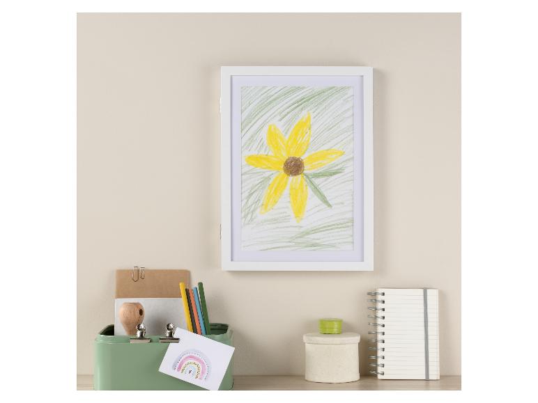 Ein gerahmtes Bild einer Blume, Stifte, ein Notizbuch und eine Metalldose.