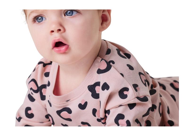 Baby in einem rosa Strampler mit Leopardenmuster.