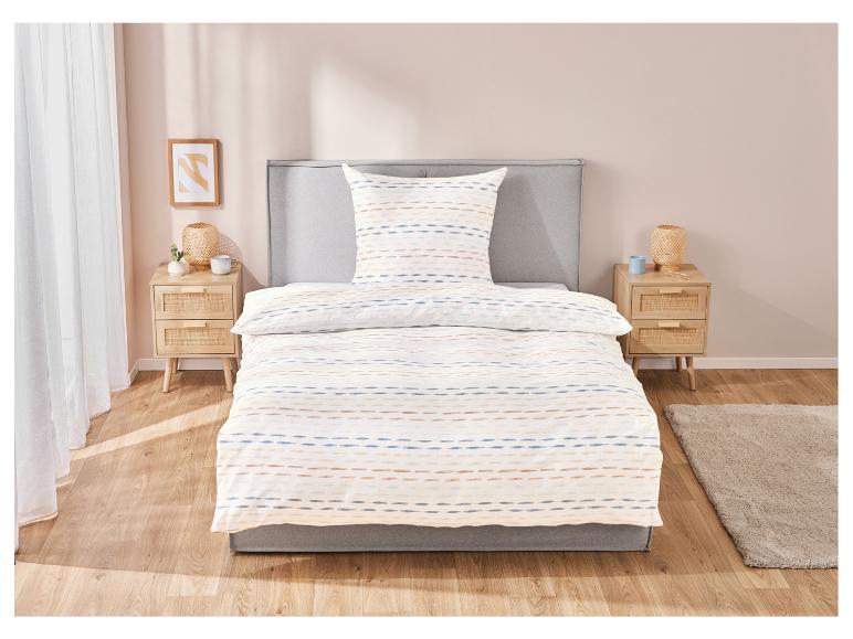 Bettwäsche und Kissen mit blauen und beigen Streifen in einem Schlafzimmer.