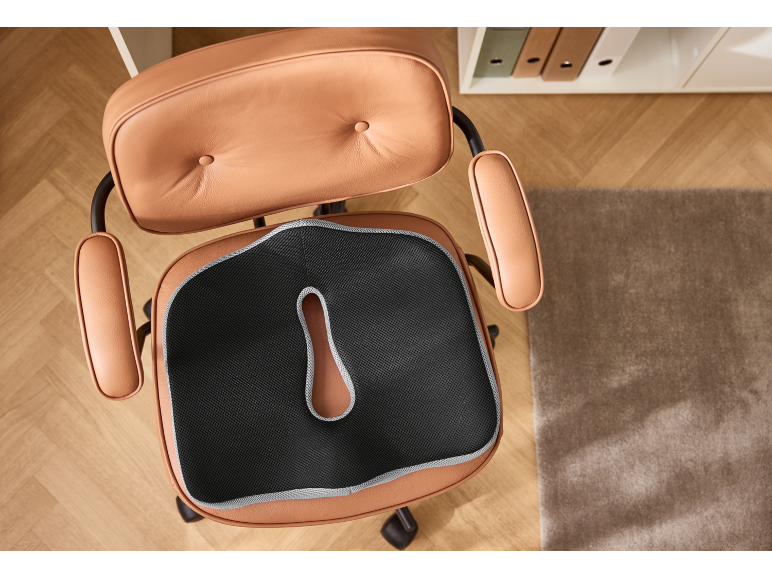 Ergonomisches Kissen auf braunem Leder-Bürostuhl, Draufsicht.