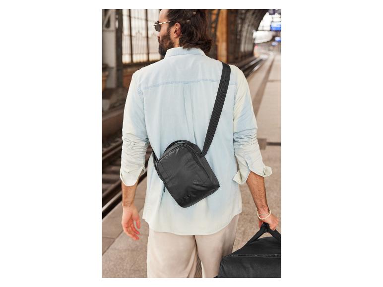 Schwarze Umhängetaschen und Reisetasche am Bahnhof.