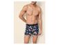 Mann oberkörperfrei in blauen Boxershorts mit orangefarbenem Blumenmuster.