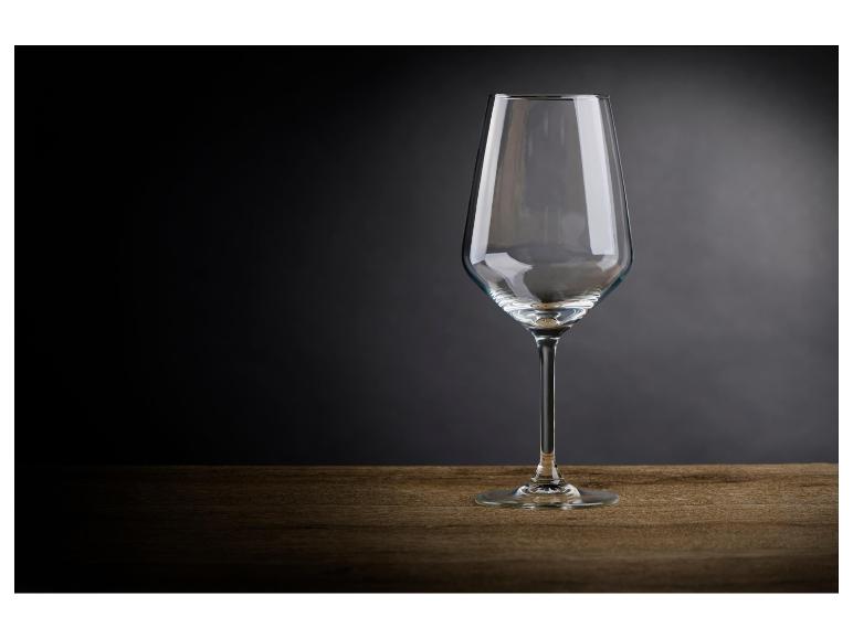 Ein leeres Weinglas auf einem Holztisch vor dunklem Hintergrund.