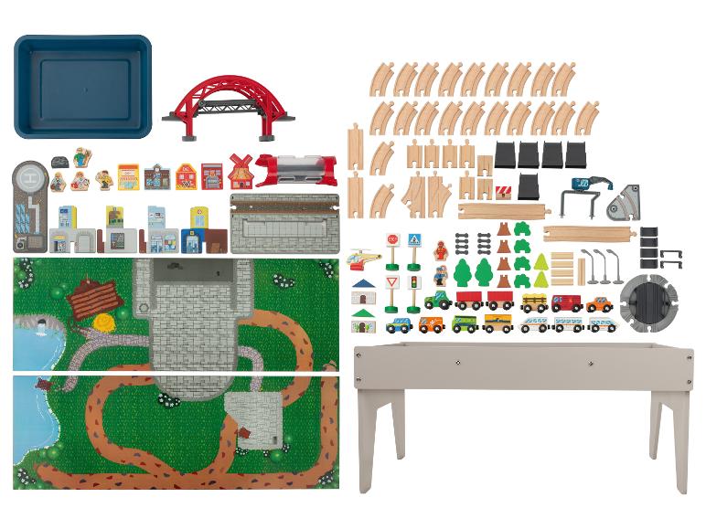 Holzeisenbahn-Spielset mit Schienen, Fahrzeugen, Gebäuden und Zubehör, plus einem Spieltisch.