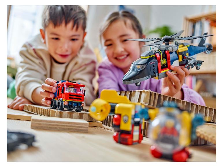 Zwei Kinder spielen mit Bauspielzeug, darunter ein Hubschrauber und ein Feuerwehrauto.