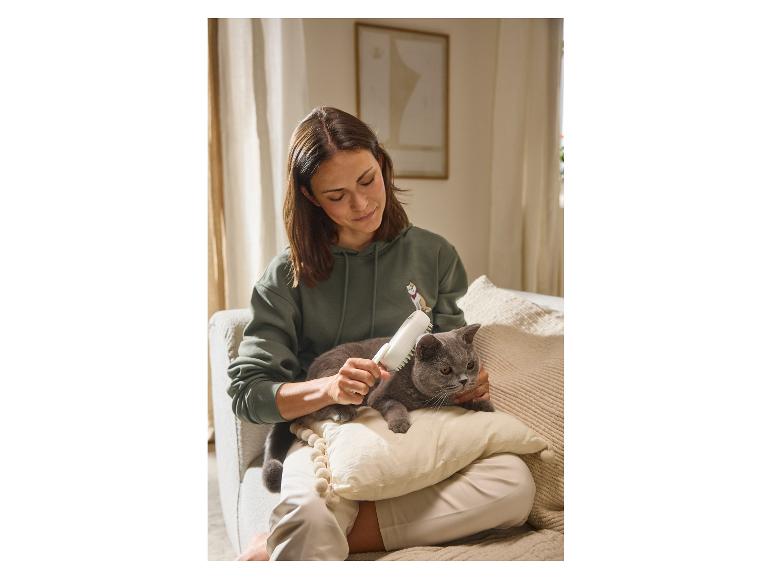 Eine Frau bürstet ihre graue Katze auf dem Schoß mit der MAX & MILA'S WORLD Tierhaarbürste mit Dampf.