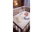 Schlafendes Baby im Kinderbett, gekleidet in einen Schlafsack mit Tiermuster.