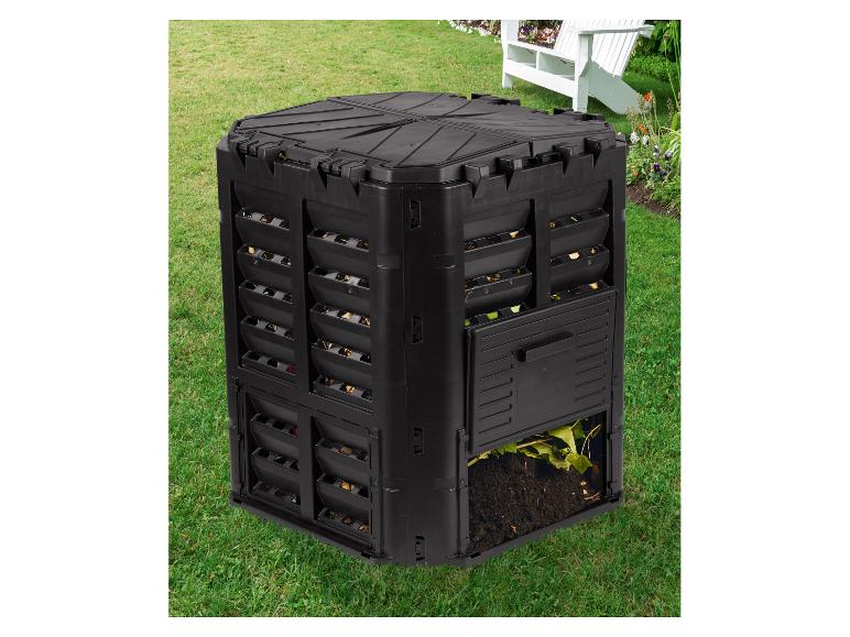 Schwarzer Komposter im Garten mit geöffneter unterer Klappe, die kompostierte Erde und Blätter zeigt.