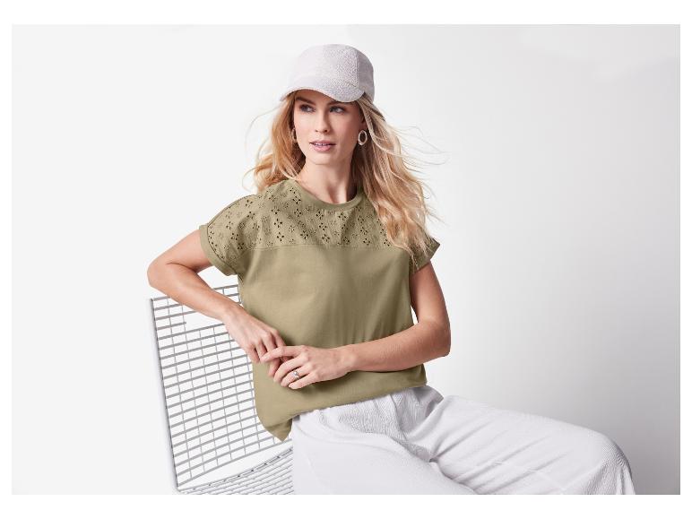 Frau in hellgrünem Shirt mit Lochmuster und weißer Hose.