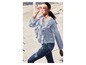 Eine Frau trägt eine hellblaue Bluse mit Rüschen und Jeans.