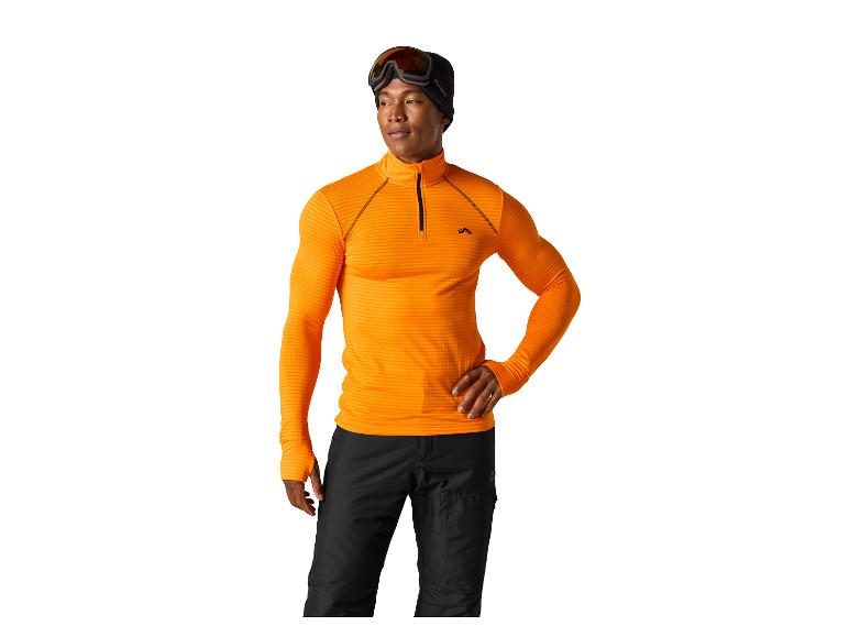 Mann in orangefarbenem Reißverschlussoberteil und schwarzer Skihose, mit Skibrille und Mütze.