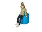 Lächelndes Kind in grünem Dinosaurier-Hoodie und Jeans, sitzend auf einem blauen Hocker.