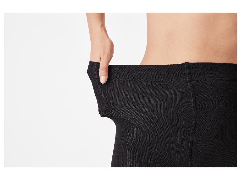 Person zieht am Bund einer schwarzen Strumpfhose, um die Elastizität zu zeigen.