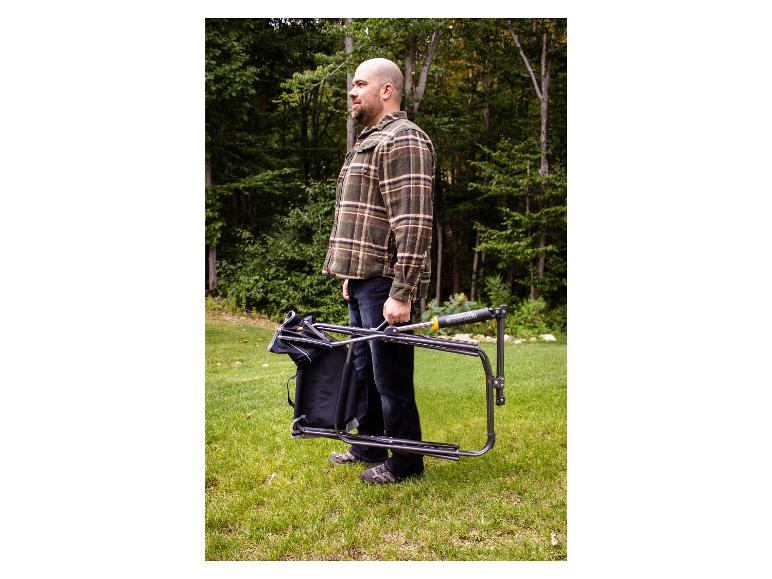 Ein Mann hält einen zusammenklappbaren Freestyle Rocker XL Stuhl im Gras.