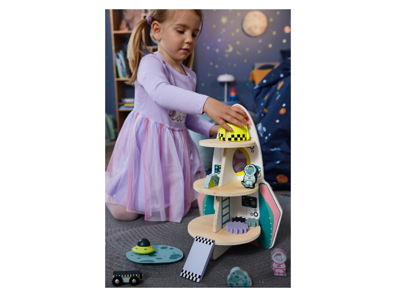 Ein Mädchen spielt mit einem hölzernen Raketenspielzeug.