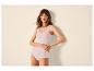Frau in hellrosa Top und Slip, Hände in die Hüften gestemmt.