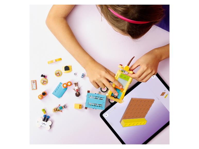 Kind baut Spielzeugauto mit bunten Bausteinen, angeleitet von einem Tablet.