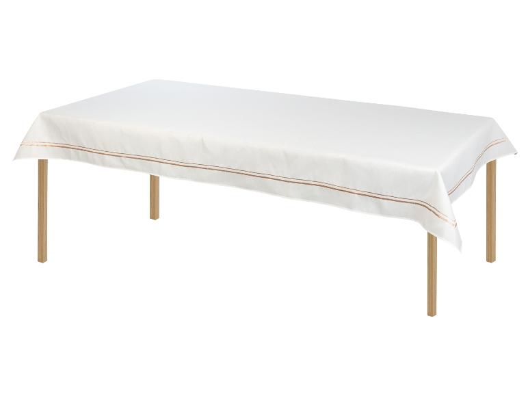 Ein weißer Tischläufer mit goldenen Streifen auf einem Holztisch.