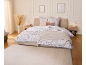 Schlafzimmer mit Bett mit floraler Bettwäsche, zwei Nachttischen und einem Teppich.