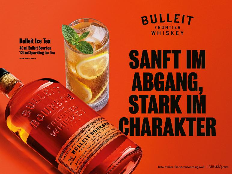 Whisky- und Eistee-Cocktail mit einer Bourbonflasche, auf orangefarbenem Hintergrund.