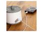 Weißes und graues Gerät mit Ladekabel, das an eine Powerbank auf einem Holztisch angeschlossen ist.
