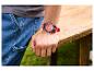 Mann trägt die PARKSIDE® Armbanduhr mit rotem Armband und lehnt an einem Holztisch.