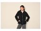 Frau in schwarzer Fleece-Kapuzenjacke, schwarzer Mütze und dunklen Jeans.