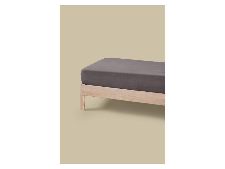 Ein Bett mit hellem Holzrahmen und dunkelgrauer Matratze.