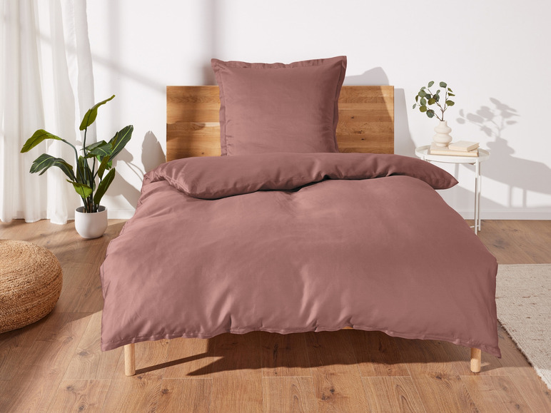 Ein rosafarbener Bettbezug mit einem Kissen auf einem Bett.