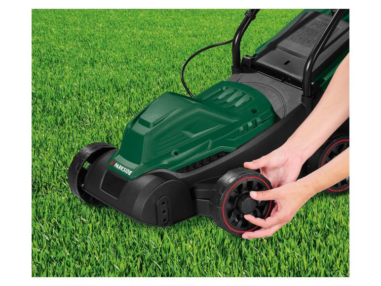 Grüner Parkside Rasenmäher auf Gras, Hände stellen Rad ein.