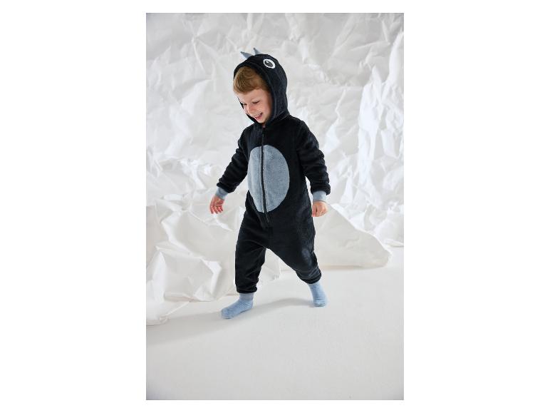 Lächelnder Junge in einem schwarzen Plüsch-Einteiler mit grauen Details.