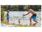 Vater und Sohn spielen mit einem Ball im Wasser, tragen Badehosen.