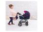 Ein Mädchen schiebt einen blauen Kinderwagen mit rosa Herzen.
