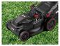 Elektrischer Rasenmäher mit roten Akzenten auf grünem Gras.