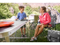 Frau und Kind campen mit Klapptisch, Campingstühlen und Zelten.