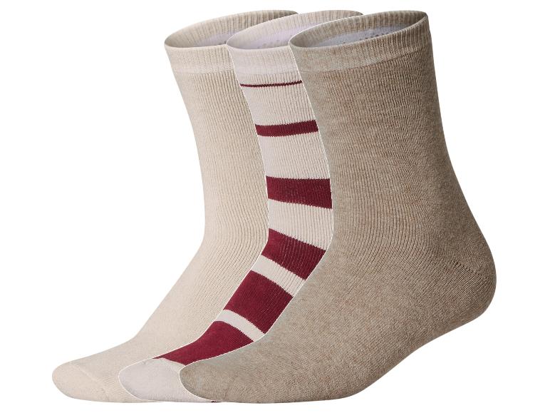 Drei Socken, eine beige, eine rot-weiß gestreift und eine hellbraun.