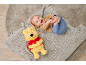 Glückliches Baby liegt auf einer Decke neben einem gelben Plüschbären