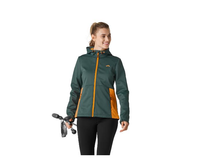 Frau in grüner und orangefarbener Jacke, hält Wanderstöcke, lächelt.
