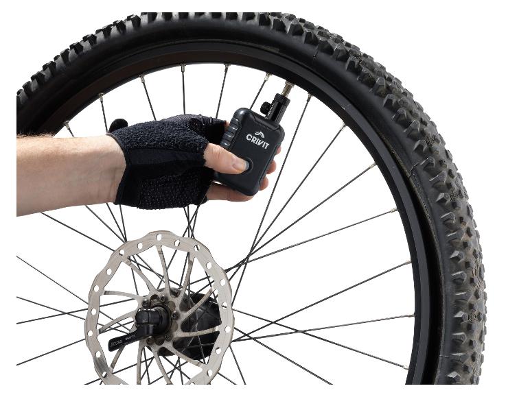 Behandschuhte Hand pumpt einen Crivit Fahrradreifen mit einer digitalen Luftpumpe auf.