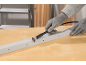 Arbeitshandschuhe schneiden ein Metallprofil mit einem Rotationswerkzeug.