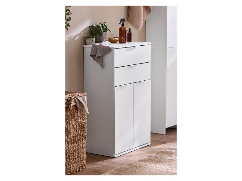 Weißer Badezimmerschrank mit Schubladen und Türen, Pflanzen und braunen Flaschen oben.