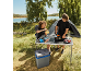 Paar kocht auf dem Campingplatz an einem Klapptisch, mit Zelt und Kühlbox.