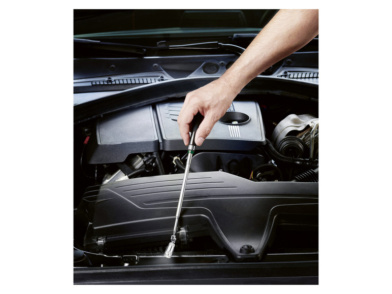 Eine Hand hält eine magnetische Taschenlampe, um in den Motorraum eines Autos zu leuchten.