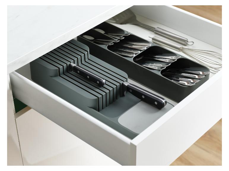 Eine offene Küchenschublade mit einem grauen Besteckkasten und Messerblock, der verschiedene Utensilien enthält.